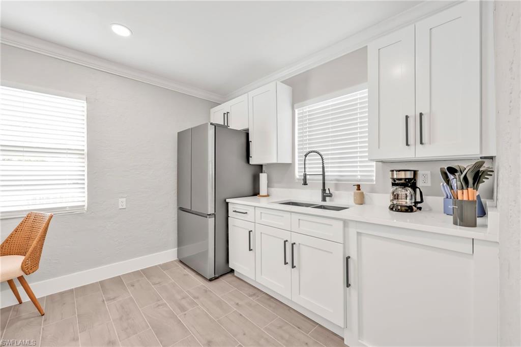 Kitchen featuring freestanding refrigerator, white cabinets, crown molding, wood tiled floors, and plenty of natural light