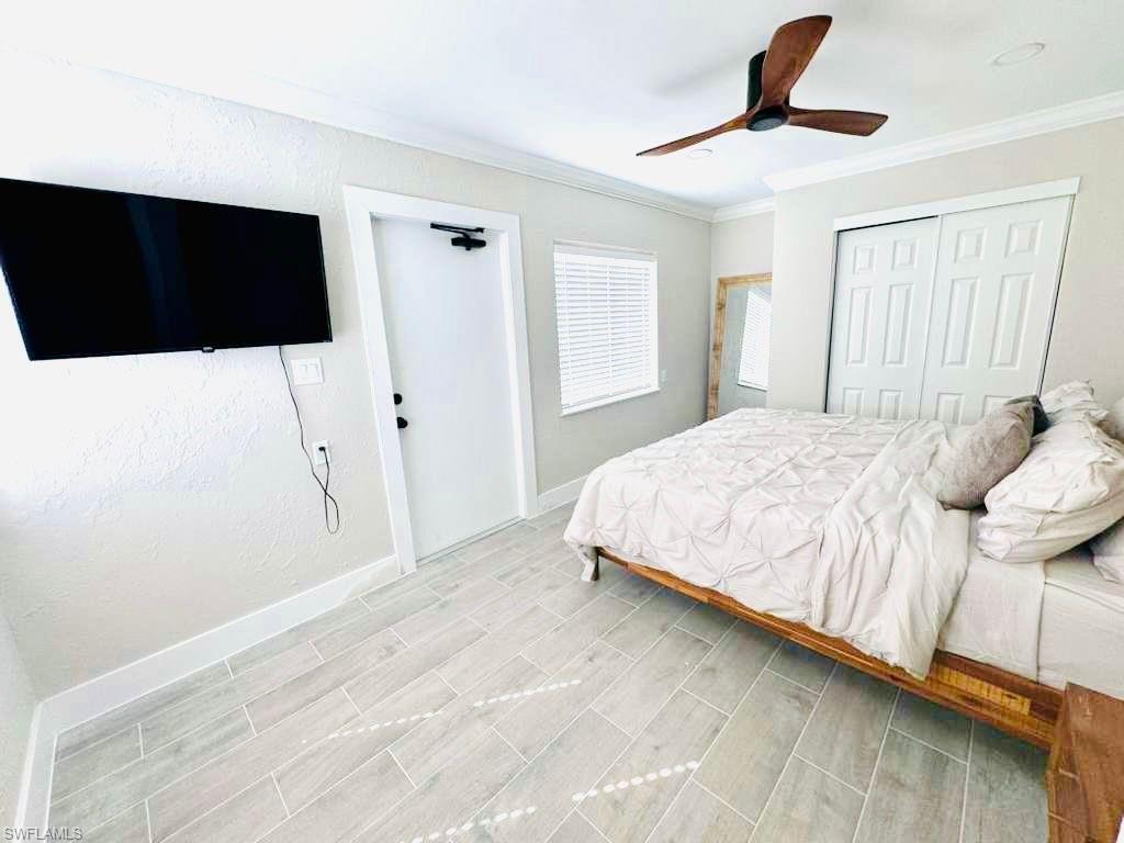 Bedroom with ornamental molding, a closet, a ceiling fan, and wood tiled floors