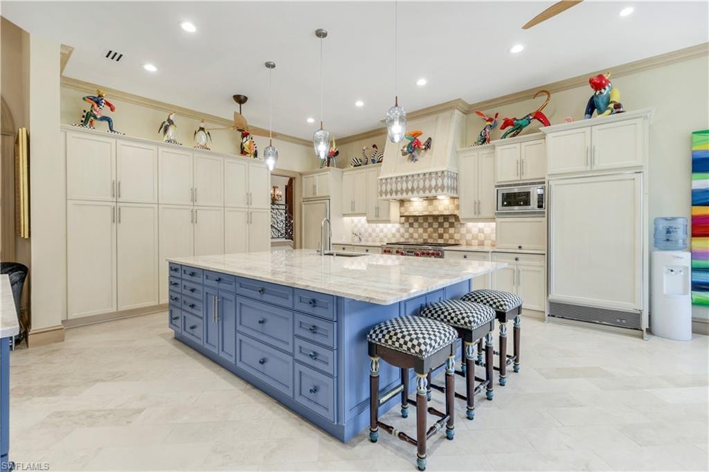 Kitchen with pendant lighting, blue cabinetry, a kitchen breakfast bar, light stone counters, and recessed lighting