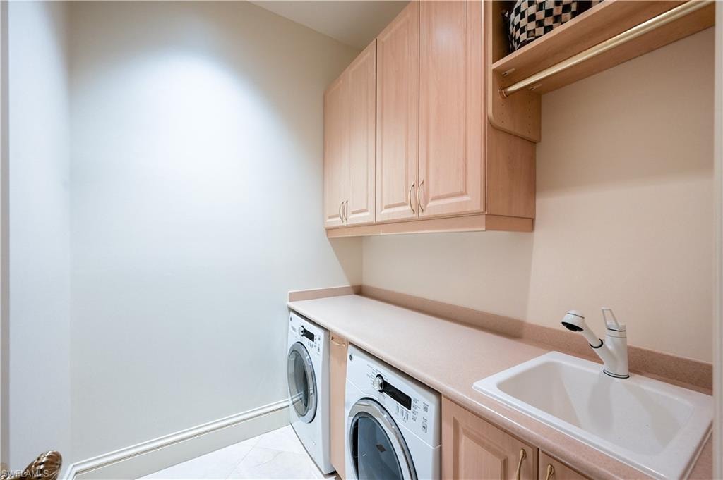 Primary bedroom laundry room with cabinet space, washer and clothes dryer, and light tile patterned floors