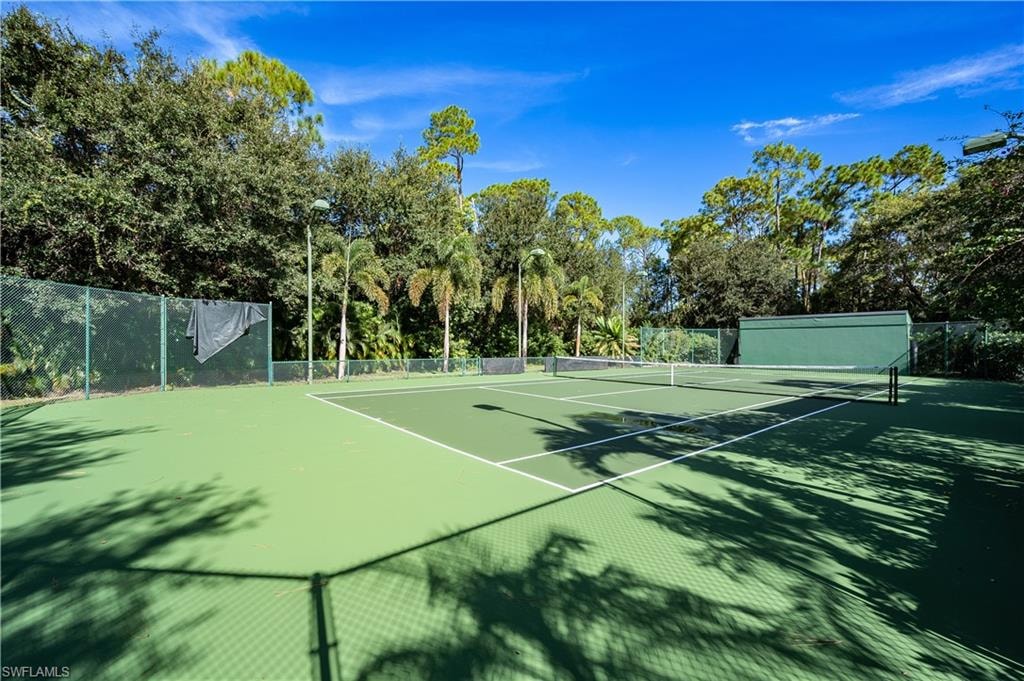 View of tennis court with view of scattered trees and community basketball court
