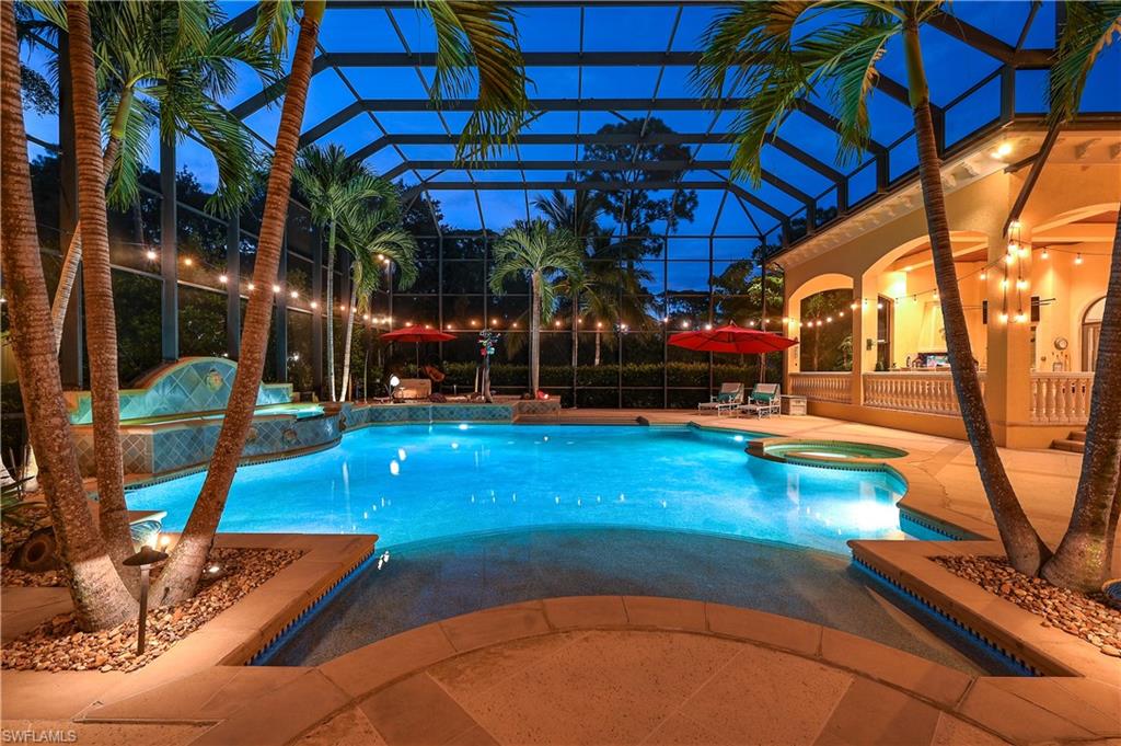 Pool at twilight featuring a pool with connected hot tub, a patio area, glass enclosure, and a sunroom