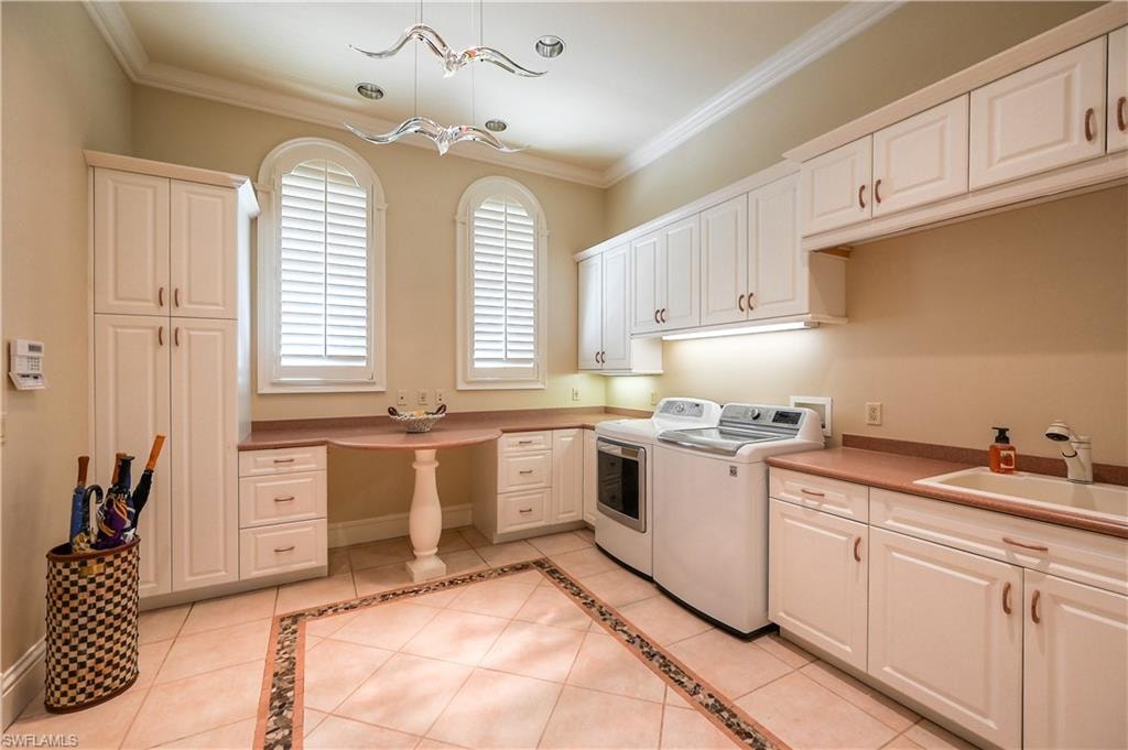 Main Laundry Room with white cabinetry, light tile patterned floors, inlaid floor details, ornamental molding, and separate washer and dryer