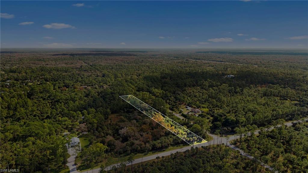 Aerial view of property and surrounding area featuring a forest and property parcel outlined