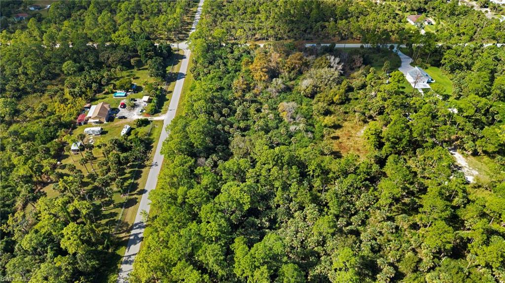 Aerial view of property and surrounding area with a forest