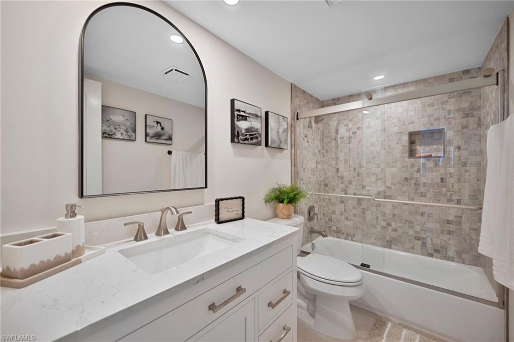 Bathroom featuring vanity, combined bath / shower with glass door, and recessed lighting
