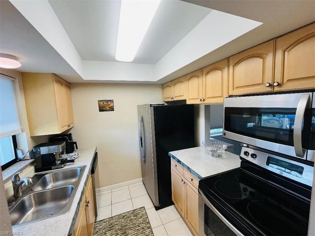 Kitchen featuring stainless steel appliances, light brown cabinetry, light tile patterned flooring, and light countertops