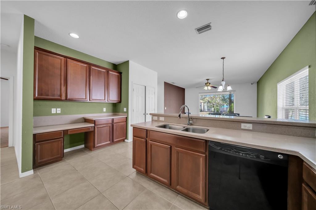 Kitchen featuring black dishwasher, built in study area, light tile patterned floors, hanging light fixtures, and recessed lighting