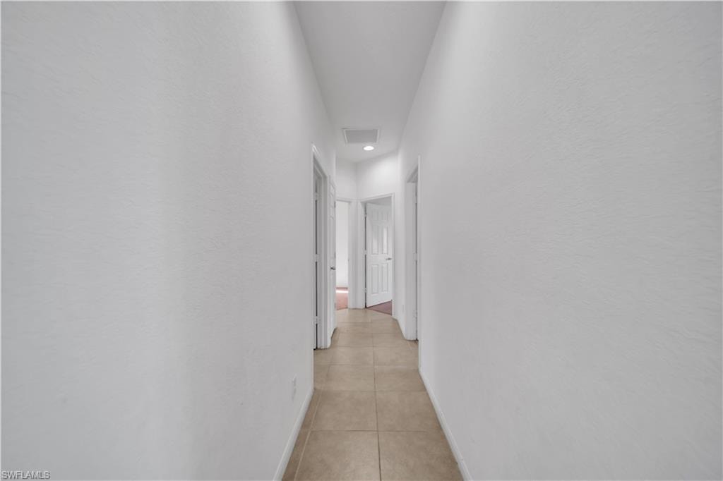 Corridor featuring light tile patterned floors and baseboards