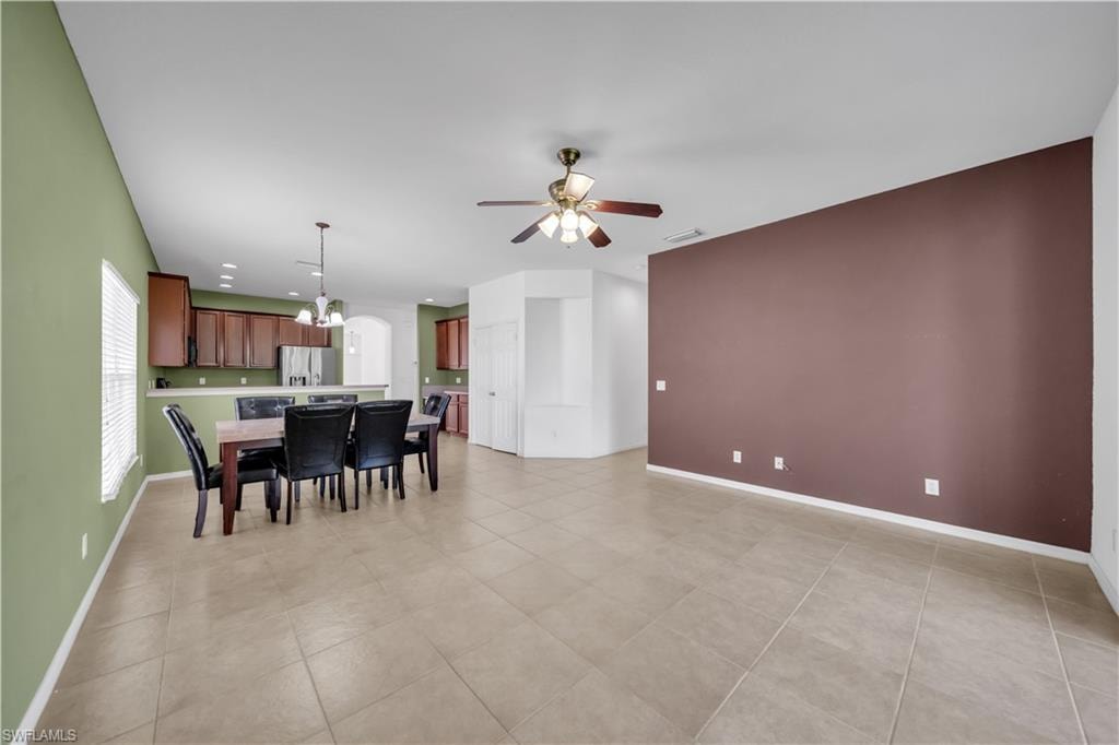 Dining space featuring a chandelier, light tile patterned floors, a ceiling fan, and arched walkways