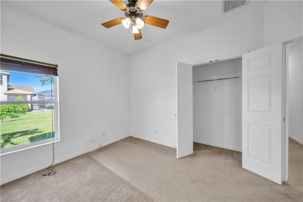 Unfurnished bedroom with light colored carpet, ceiling fan, and a closet