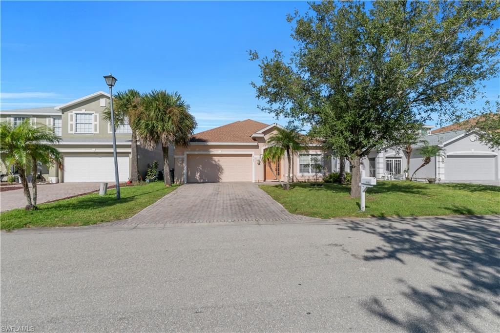 View of front of house featuring decorative driveway, a front yard, stucco siding, and a garage