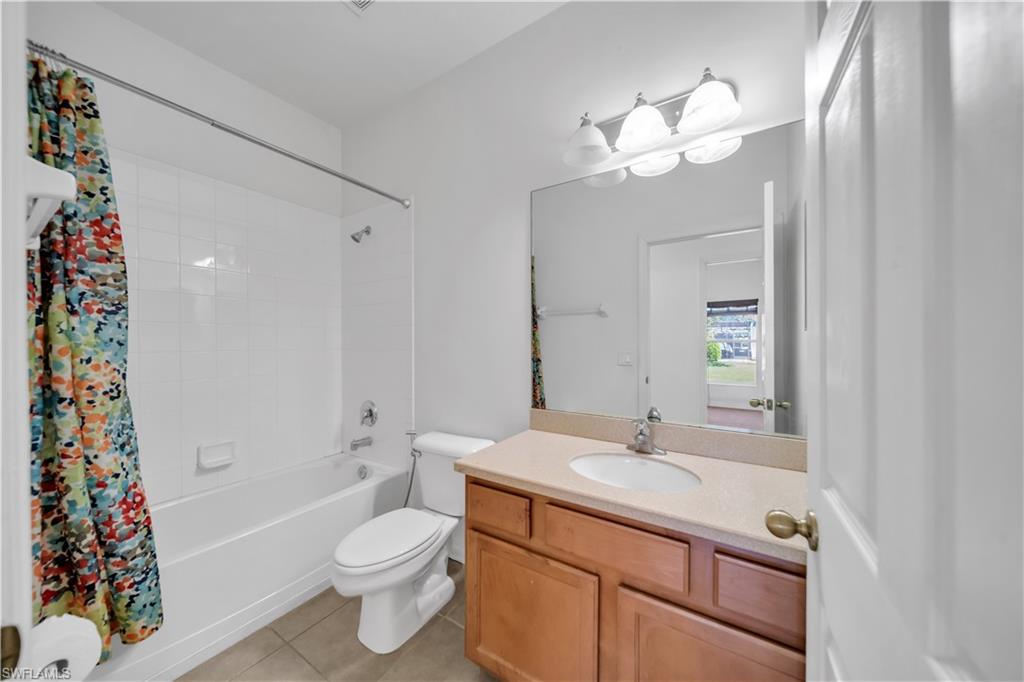 Bathroom featuring shower / bath combo with shower curtain, light tile patterned floors, and vanity
