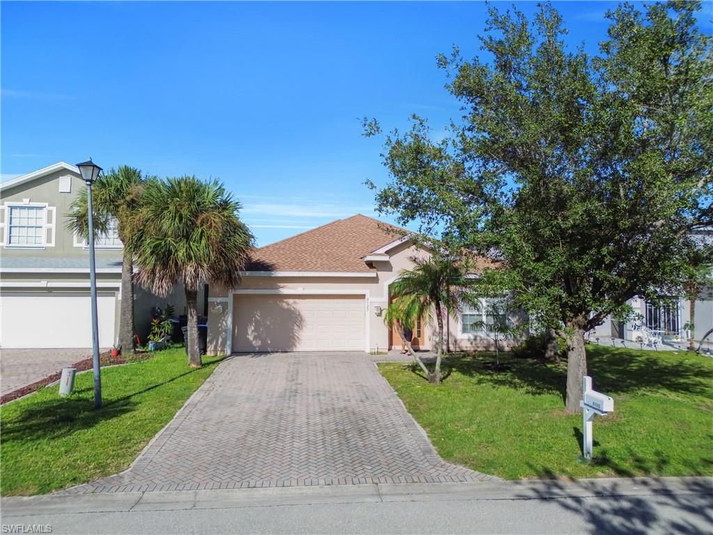 View of front of home featuring a front yard, stucco siding, decorative driveway, and an attached garage