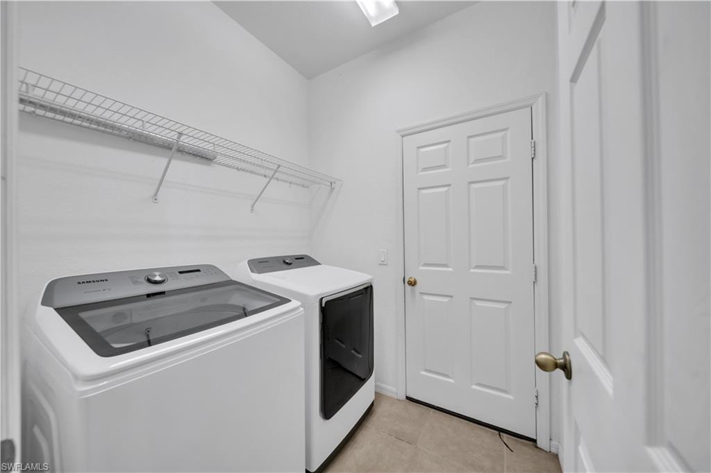 Laundry room with light tile patterned floors and washer and clothes dryer
