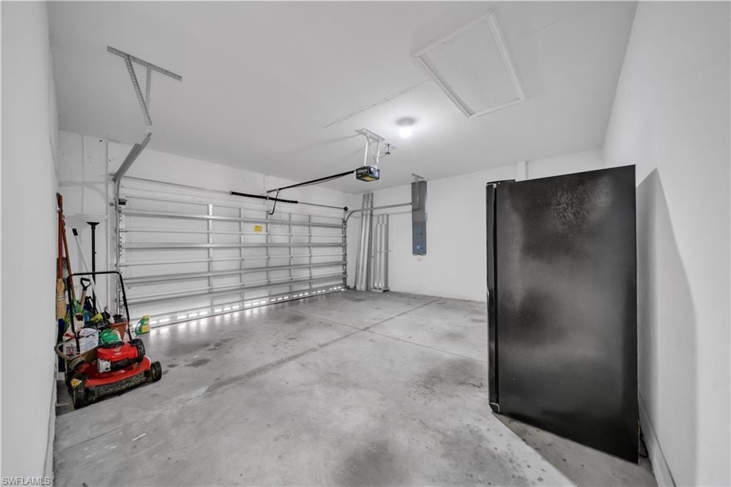 Garage featuring freestanding refrigerator and electric panel