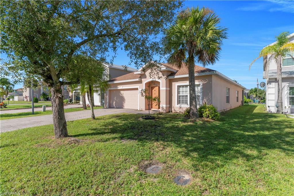 View of front facade featuring stucco siding, decorative driveway, a garage, and a front lawn