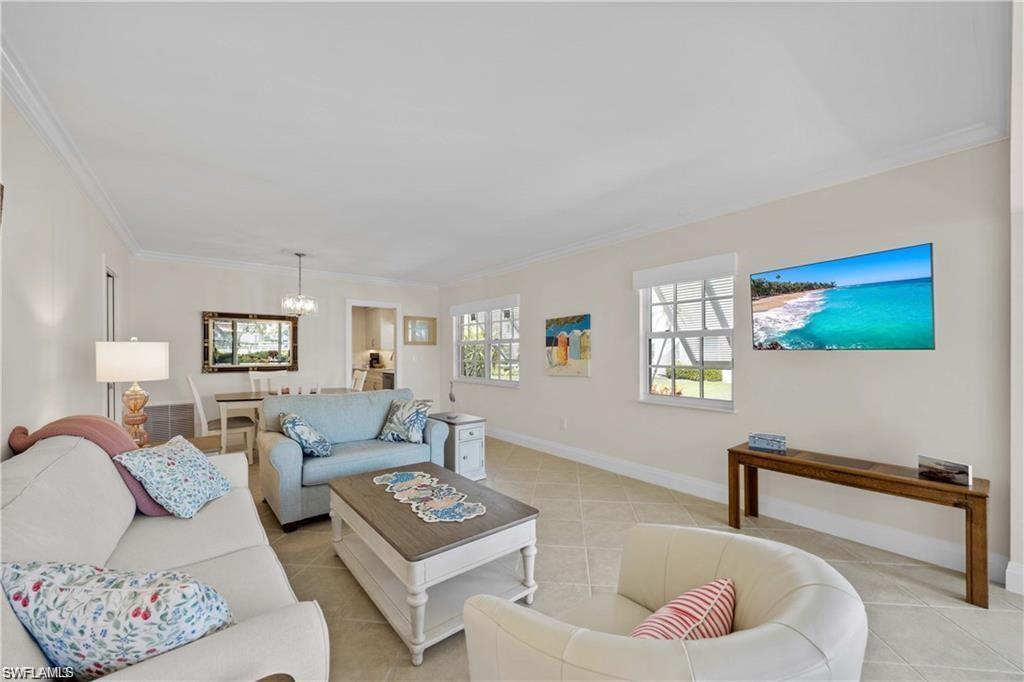 Living area featuring ornamental molding, light tile patterned floors, and a chandelier