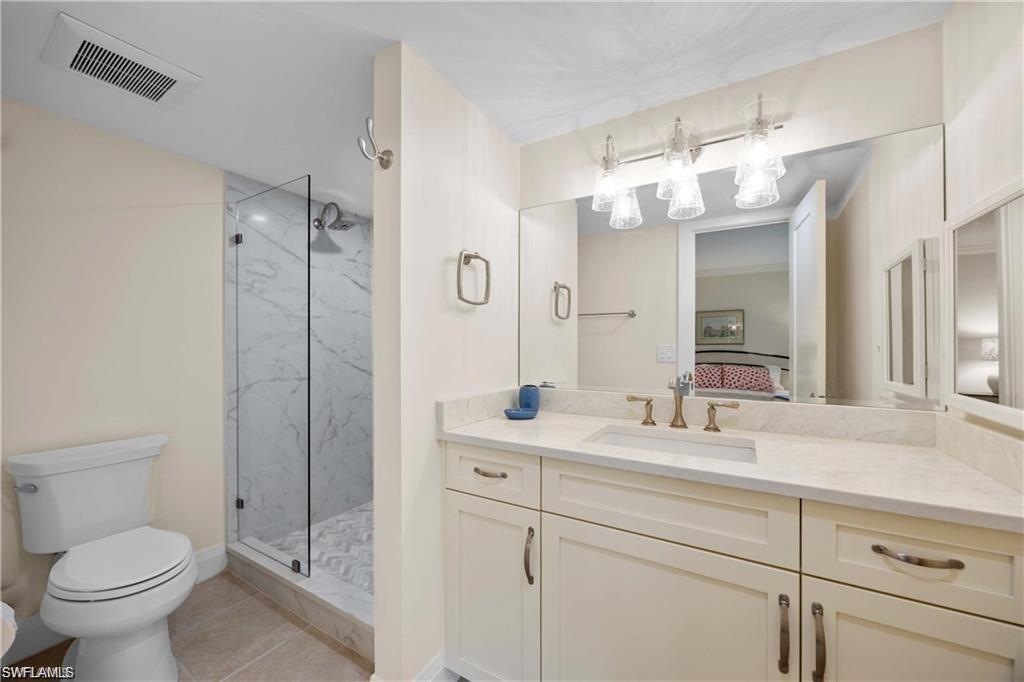 Ensuite bathroom featuring vanity, a marble finish shower, and light tile patterned flooring