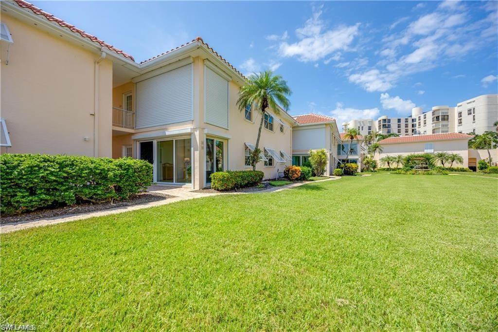Back of property featuring a lawn, a balcony, stucco siding, and a tiled roof