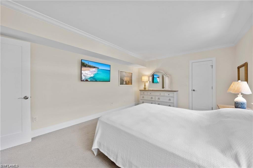 Bedroom with crown molding and light colored carpet