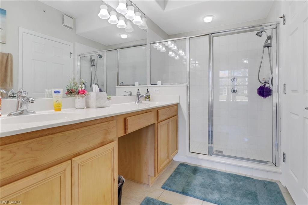 Full bathroom featuring double vanity, light tile patterned floors, and a shower stall
