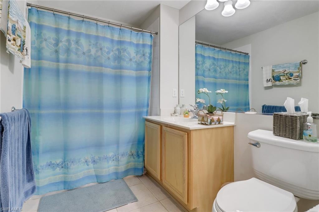 Full bathroom featuring light tile patterned floors, a shower with curtain, and vanity