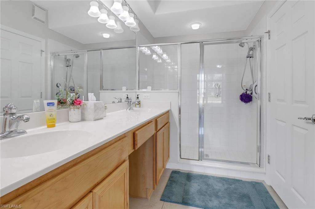 Full bathroom with double vanity, light tile patterned floors, a shower stall, and a chandelier