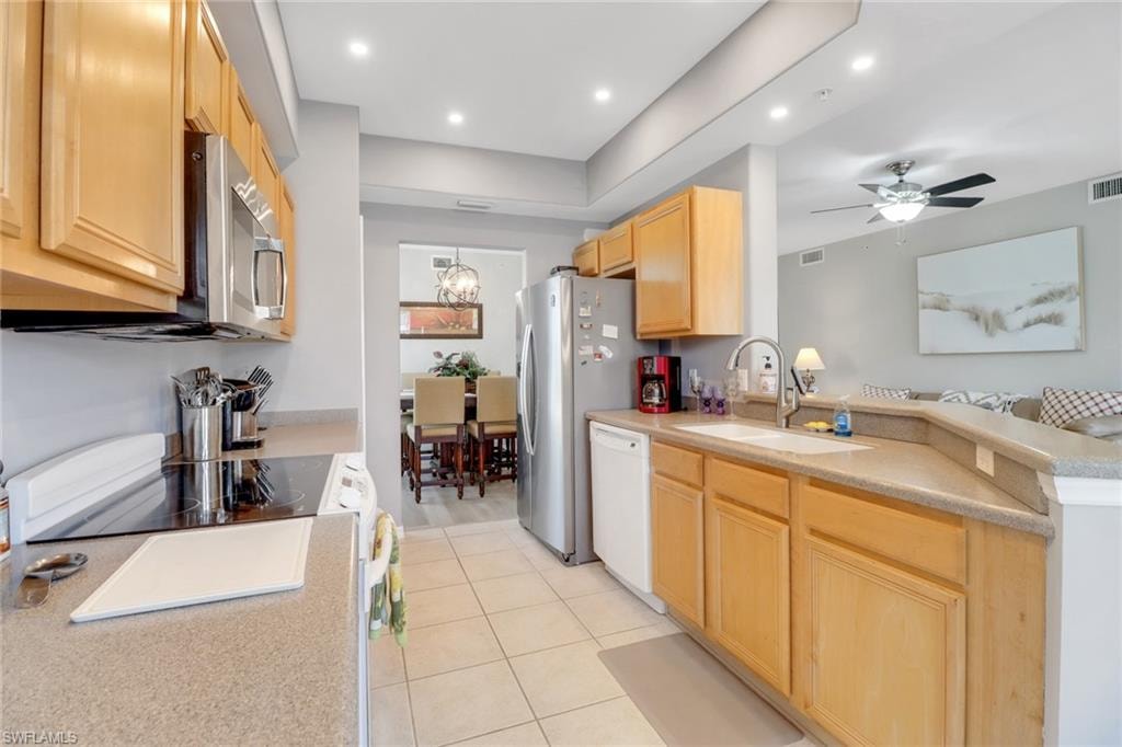 Kitchen featuring light brown cabinets, a chandelier, appliances with stainless steel finishes, hanging light fixtures, and light tile patterned floors
