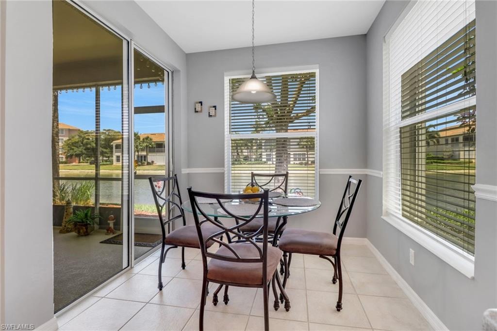 Tiled dining space featuring a water view and baseboards
