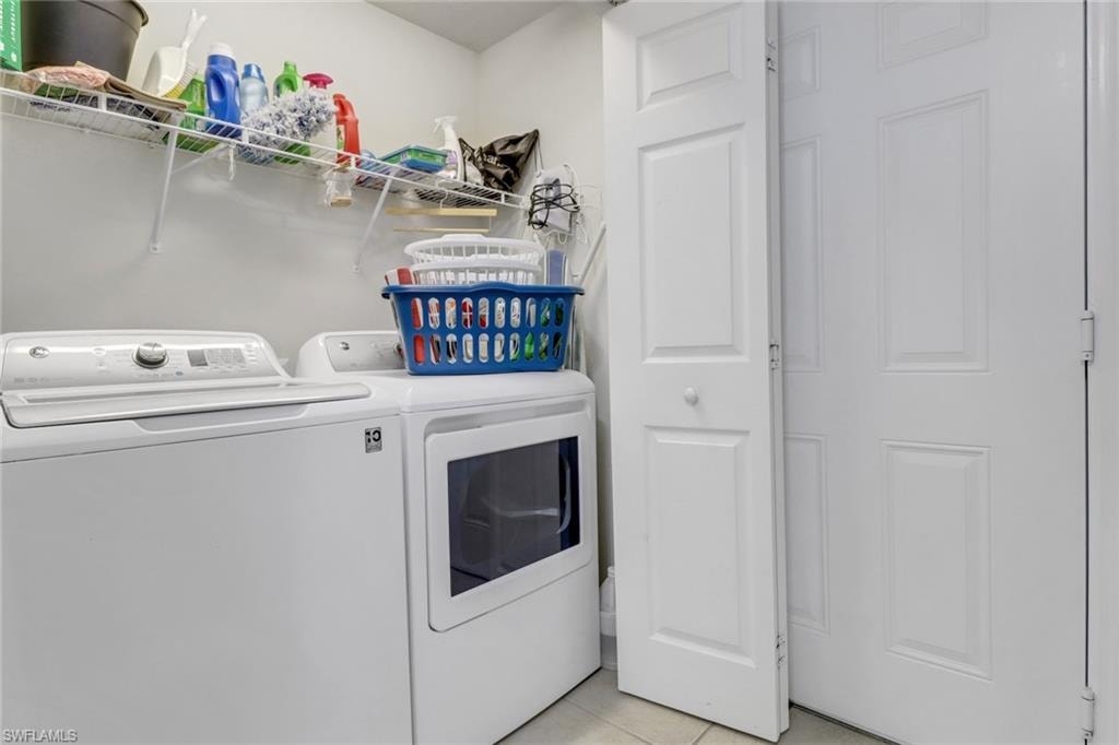 Laundry room with light tile patterned floors and washing machine and clothes dryer