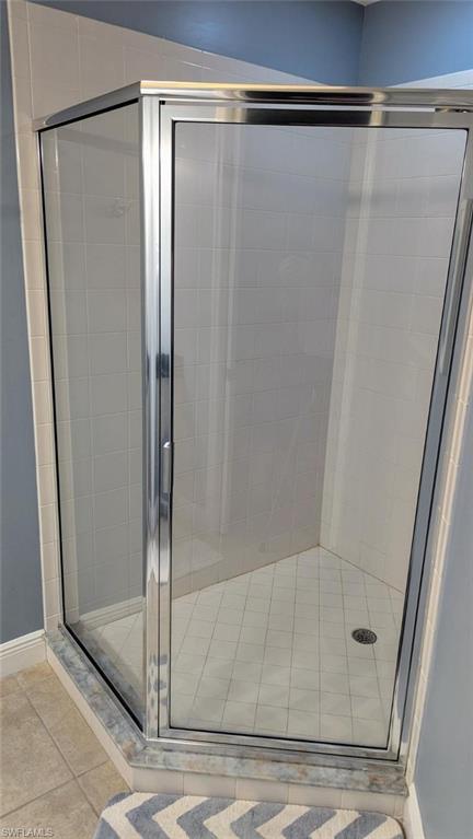 Full bath with a shower stall and light tile patterned floors