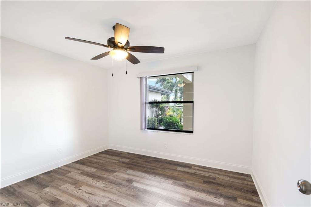 Empty room with dark wood-type flooring and a ceiling fan