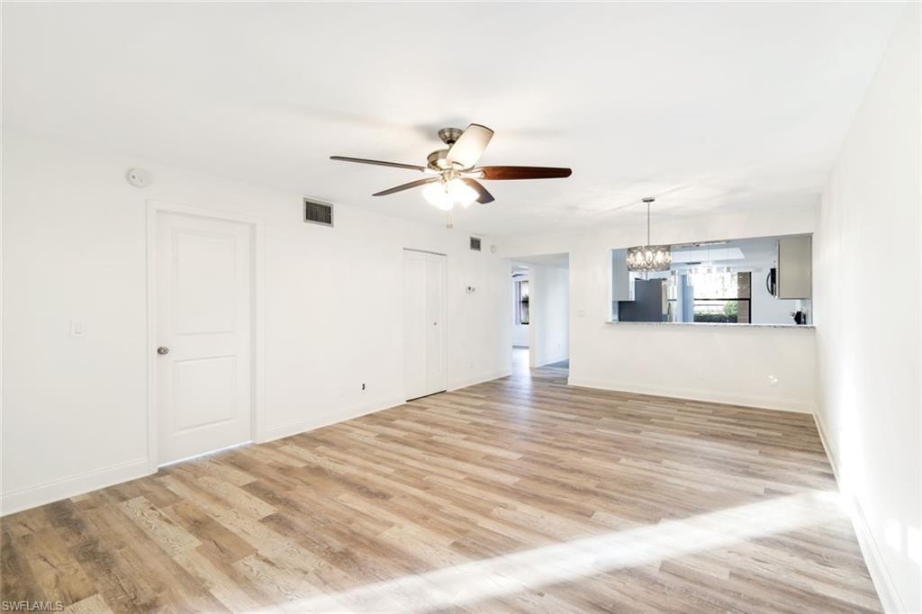 Unfurnished living room with a chandelier, light wood-style floors, and ceiling fan