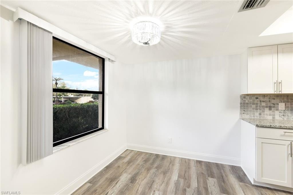 Unfurnished dining area featuring light wood finished floors and a chandelier