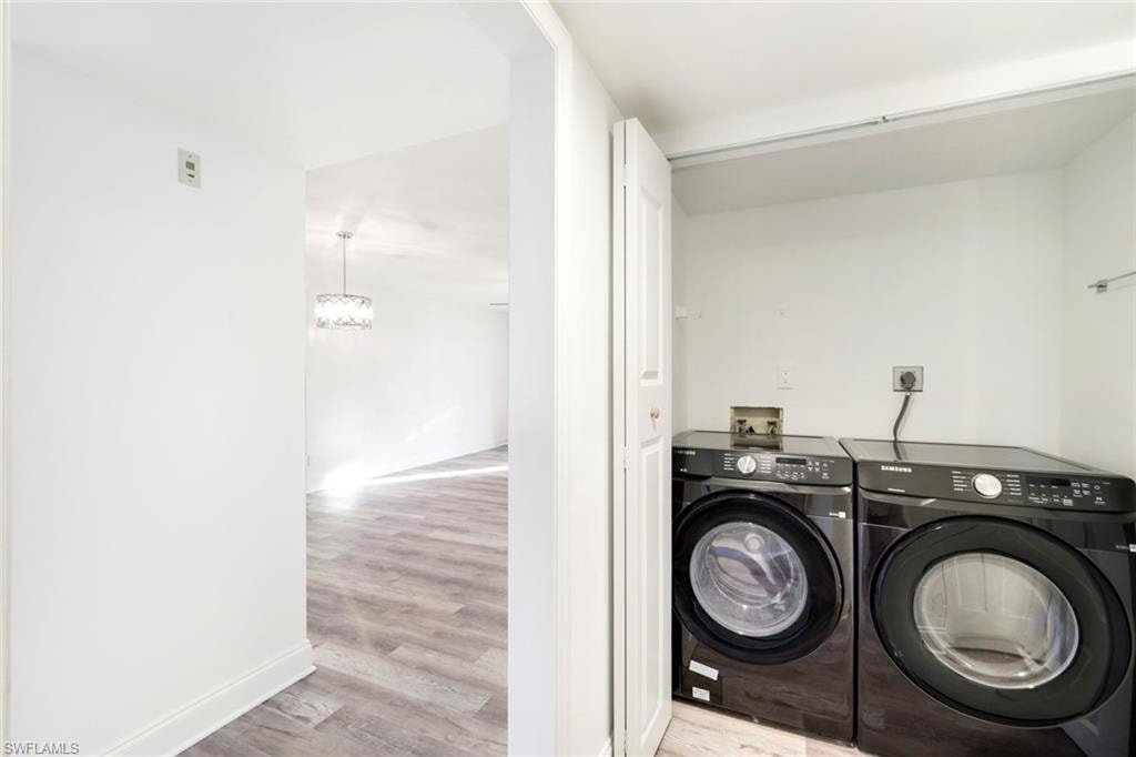 Washroom featuring light wood-style flooring, a chandelier, and separate washer and dryer