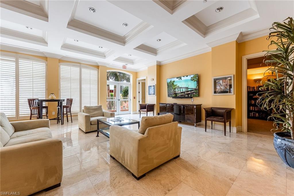 Living room with crown molding, light marble finish floors, coffered ceiling, a high ceiling, and beamed ceiling