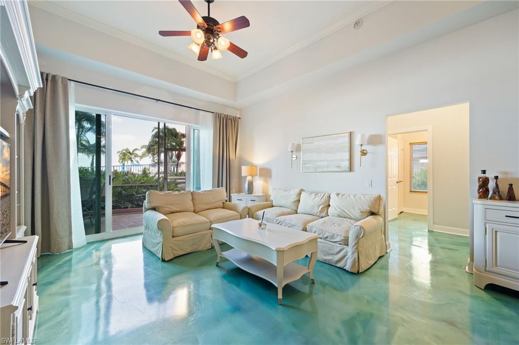 Living room with healthy amount of natural light, concrete flooring, crown molding, and a ceiling fan