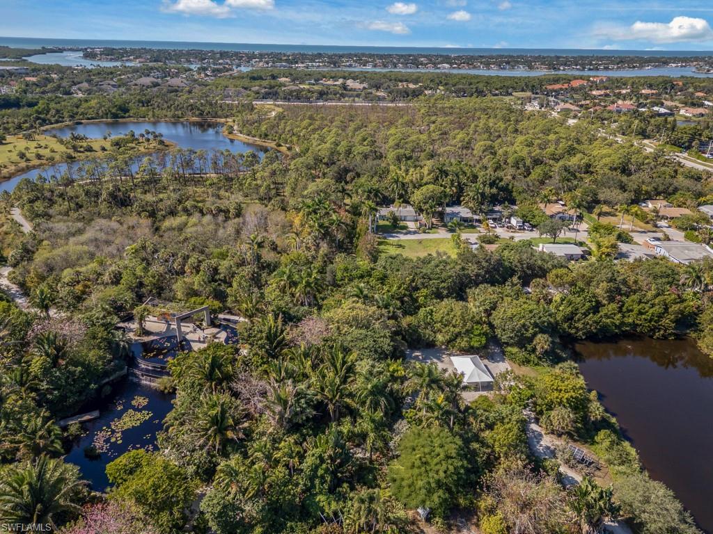 Aerial view of property and surrounding area with a nearby body of water and a heavily wooded area