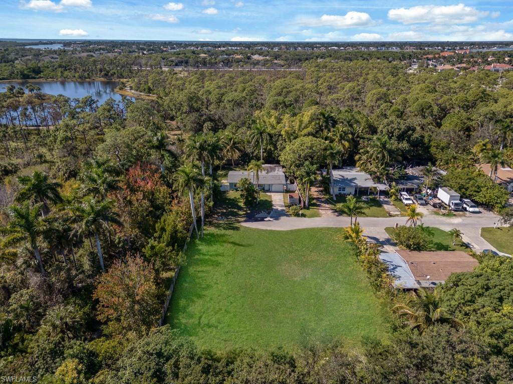Aerial overview of property's location featuring a heavily wooded area and a nearby body of water