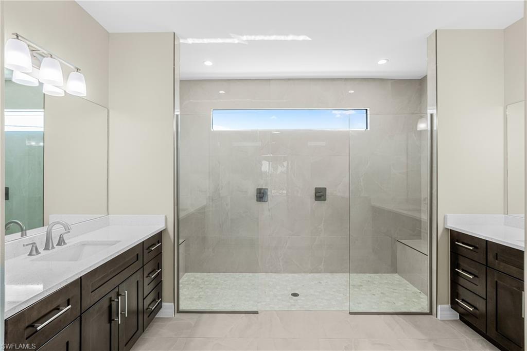 Full bath featuring two vanities, walk in shower, light tile patterned floors, and recessed lighting