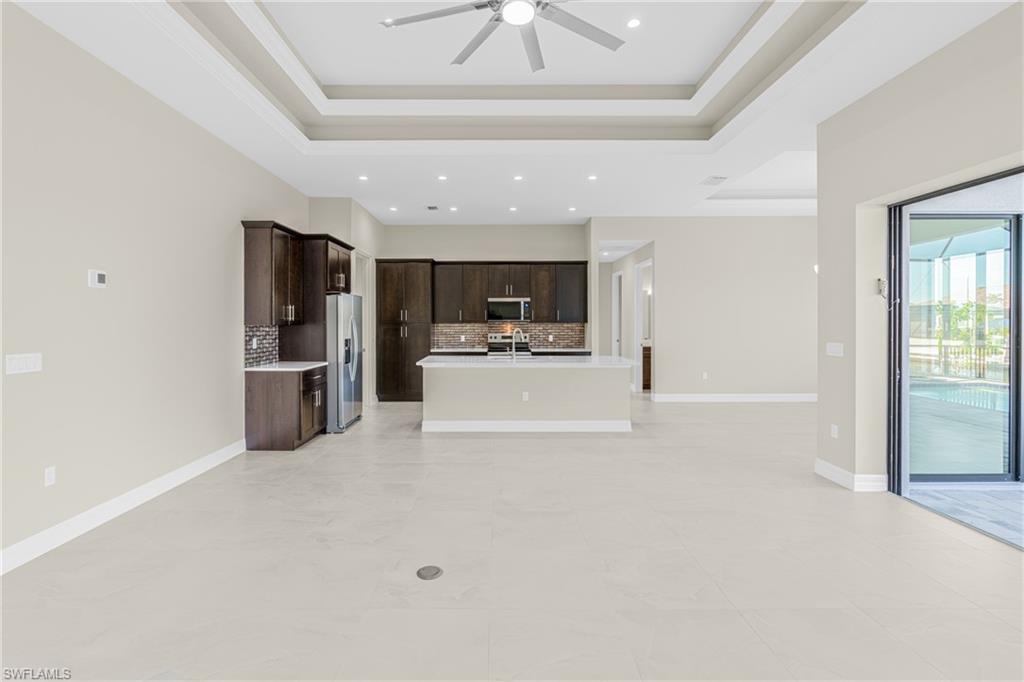 Unfurnished living room with a tray ceiling and a ceiling fan