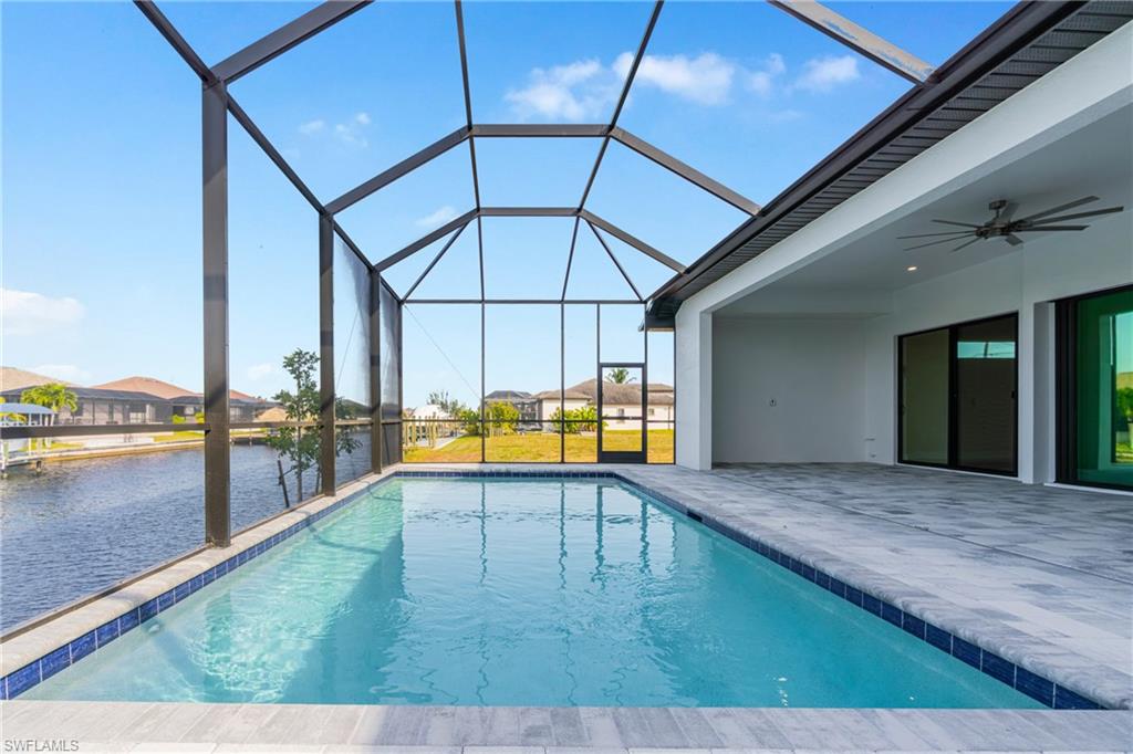 Swimming pool featuring ceiling fan, a sunroom, glass enclosure, and a patio area
