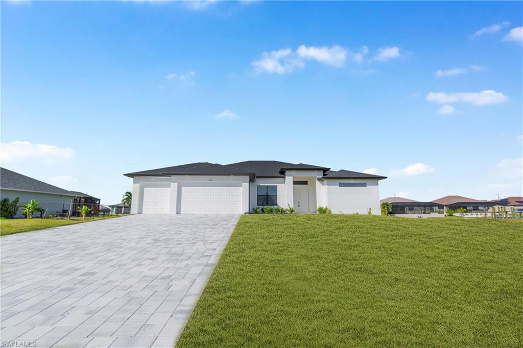 Prairie-style home with a front yard, a garage, decorative driveway, and stucco siding