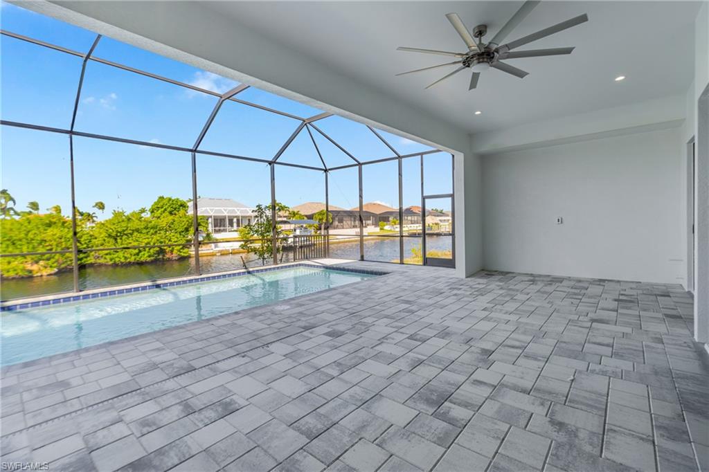 Outdoor pool featuring glass enclosure, a sunroom, a water view, a ceiling fan, and a residential view
