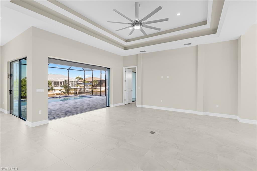 Spare room with a sunroom, a tray ceiling, and ceiling fan