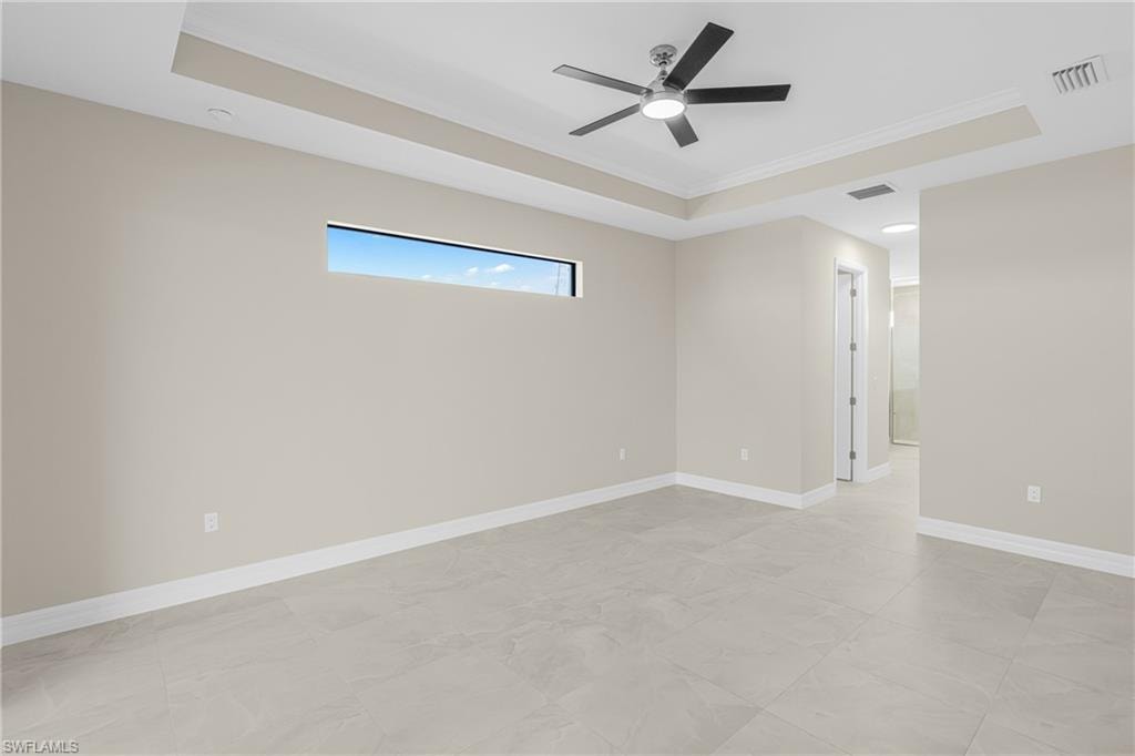 Spare room featuring a tray ceiling, ornamental molding, and ceiling fan