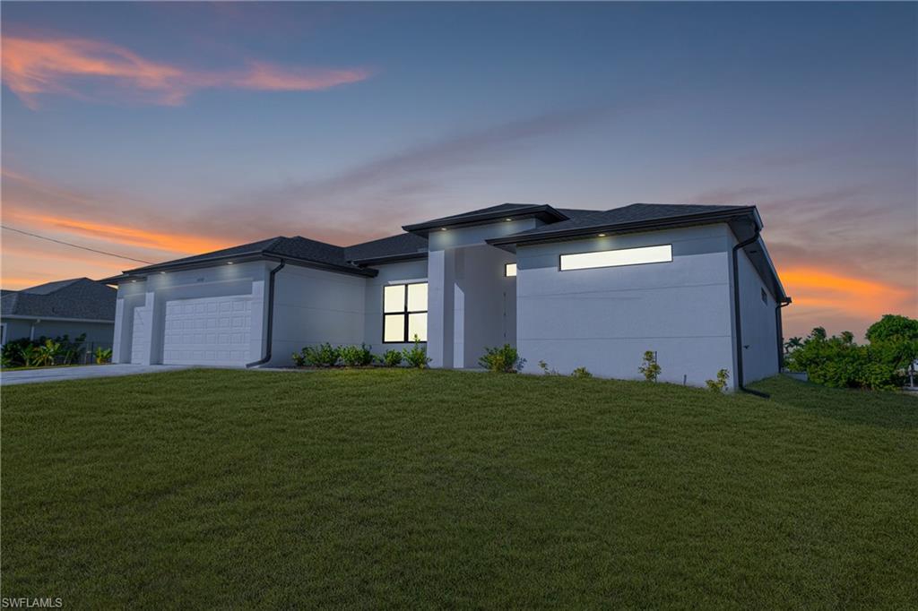 Prairie-style home with a yard, an attached garage, driveway, and stucco siding