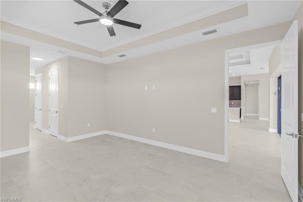 Spare room featuring a tray ceiling, ornamental molding, and ceiling fan