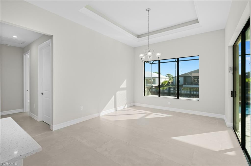 Unfurnished dining area with a raised ceiling, a chandelier, and concrete floors